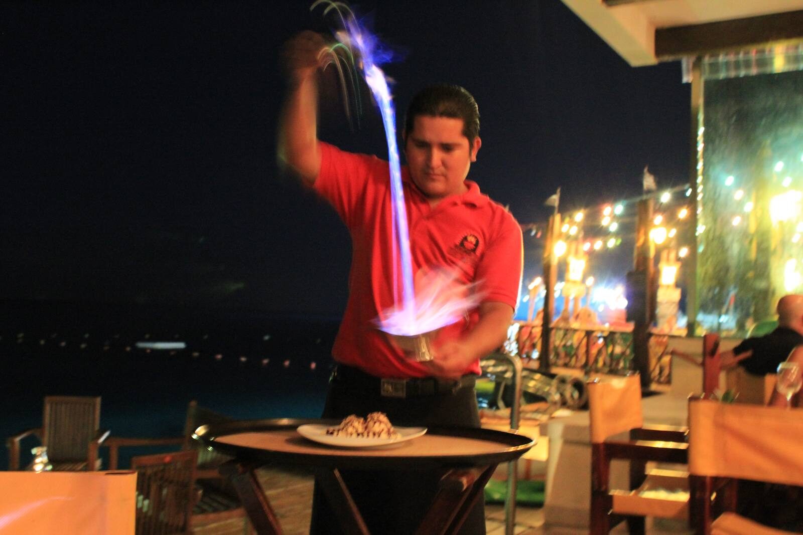A waiter pouring flaming coffee at the table in a Cozumel restaurant